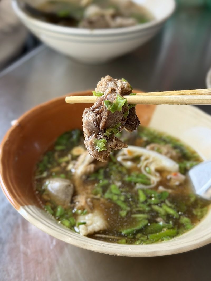 ตะเกียบคีบเนื้อเปื่อยขึ้นจากชามน้ำซุปหอมสมุนไพร
