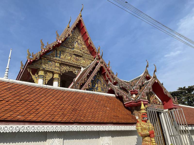 หน้าบันลายทองของโบสถ์และหลังคากระเบื้องสีส้ม ตัดกับฟ้าสีคราม